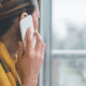 Person on phone near window wearing yellow scarf